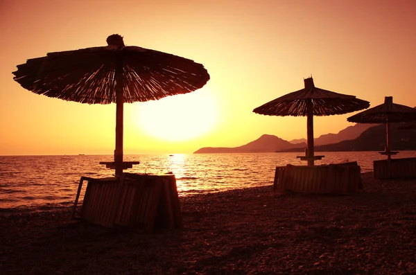 Hermosa playa con tumbonas y sombrilla al atardecer — Foto de Stock