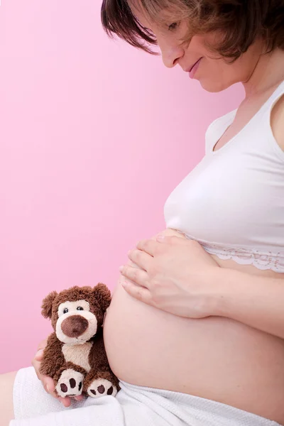 Mujer embarazada con oso de peluche — Foto de Stock