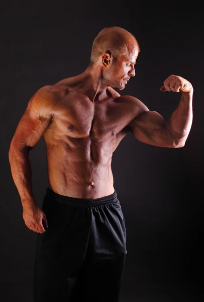 Der muskulöse Bodybuilder, der den Bizeps beugt — Stockfoto