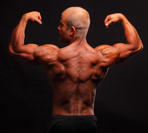 Der muskulöse Bodybuilder, der den Bizeps beugt — Stockfoto