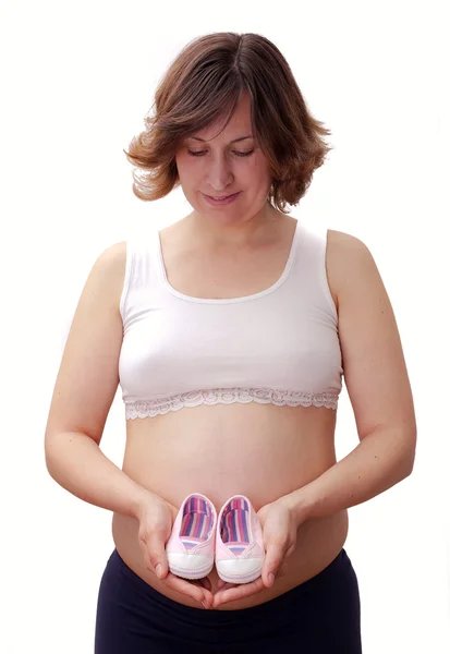 Femme enceinte avec des chaussures de bébé sur le ventre — Photo