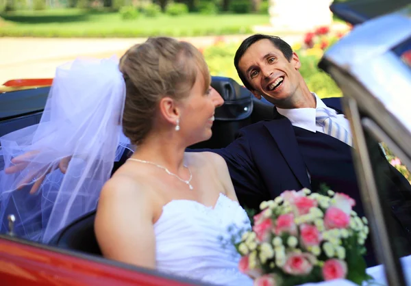 Jeune couple de mariage assis dans une voiture cabriolet — Photo