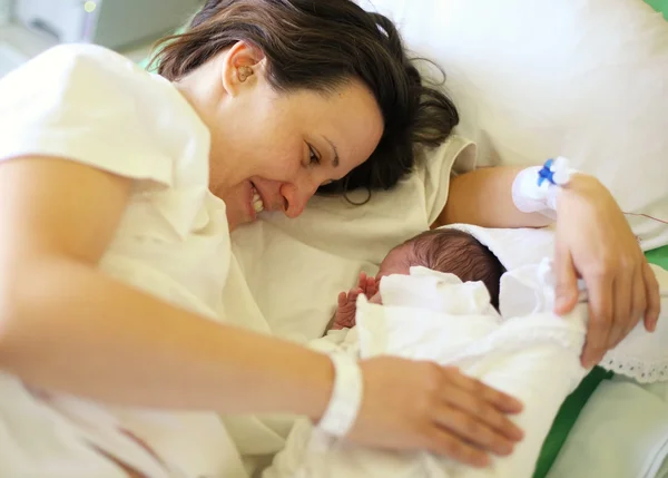 Happy mother with her newborn baby on hospital bed — Stock Photo, Image