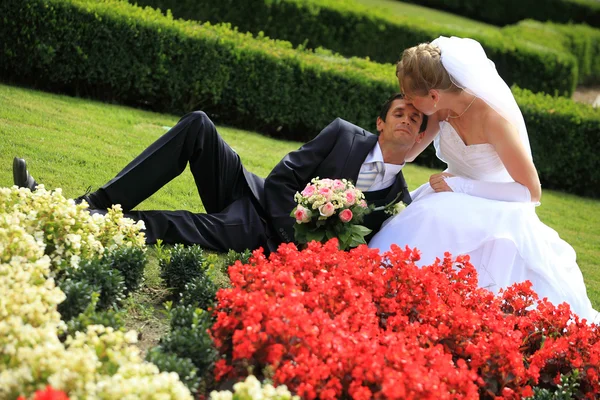 Young wedding couple lying on grass in garden — Stock Photo, Image