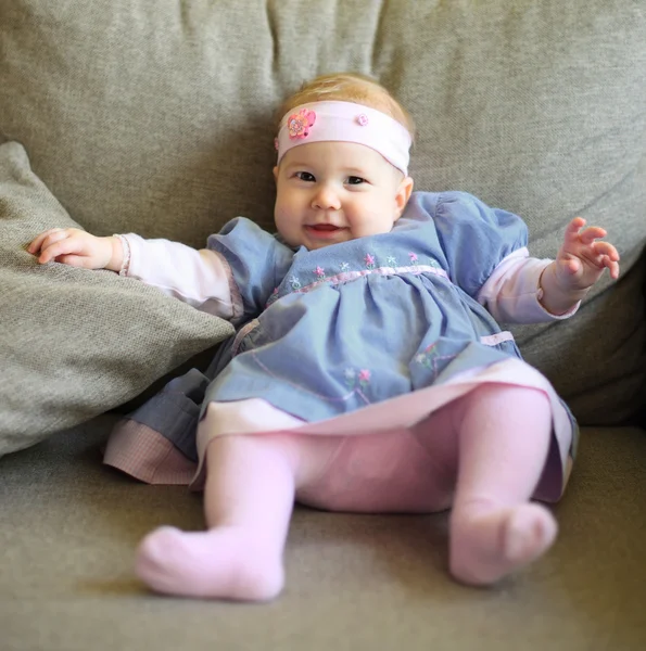 Cute baby in pretty cloth sitting on couch — Stock Photo, Image