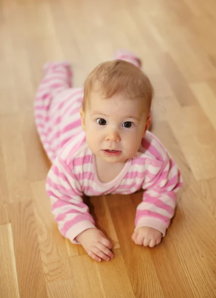 Cute baby lying on parquet floor — Stock Photo, Image