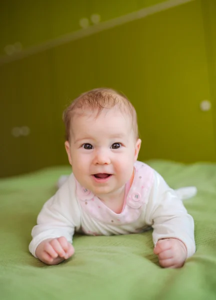 Roztomilý usměvavý miminko leží na postelisöta leende barnet ligger på sängen — Stock fotografie