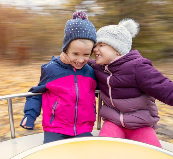 2人の若い幸せな子供メリーゴーランド屋外で秋 — ストック写真