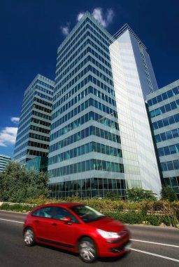 Şehrin dışındaki modern ofis binası kırmızı arabalı.