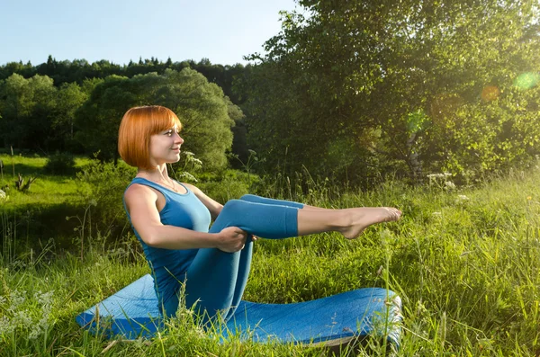 Röd kvinna utövar fitness yoga utomhus — Stockfoto