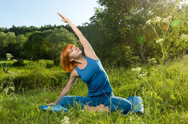 Röd kvinna utövar fitness yoga utomhus — Stockfoto