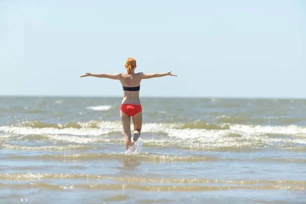 Mujer joven delgada corriendo en las olas del mar — Foto de Stock