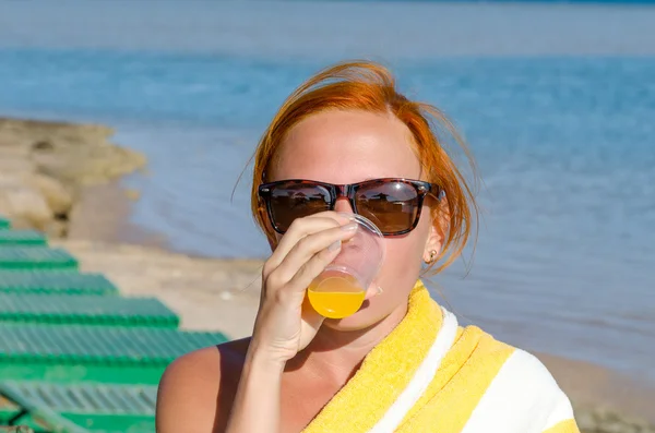 Red woman drinking orange juice Royalty Free Stock Photos