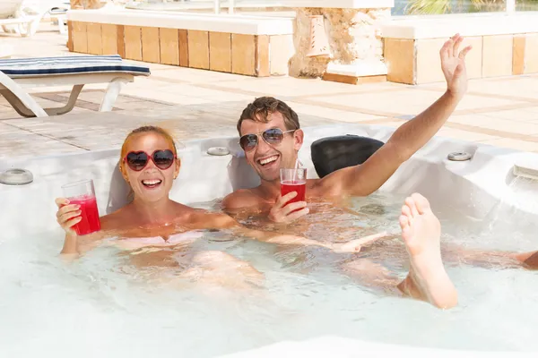 Casal jovem relaxante na piscina jacuzzi — Fotografia de Stock