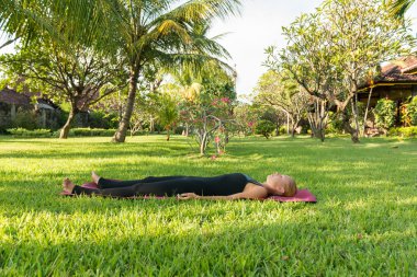 Woman doing yoga in garden clipart