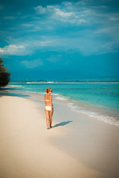 Giovane donna che cammina lungo la spiaggia tropicale — Foto Stock