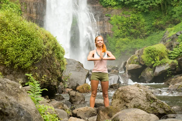 Junge Frau praktiziert Yoga am Wasserfall — Stockfoto