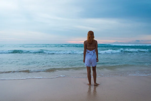 Молодая женщина стоит на берегу океана — стоковое фото