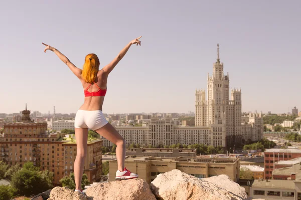 Fit young woman with raised hands above the city — Stock Photo, Image