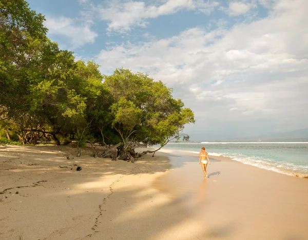 Nuori nainen kävelee pitkin trooppista rantaa — kuvapankkivalokuva