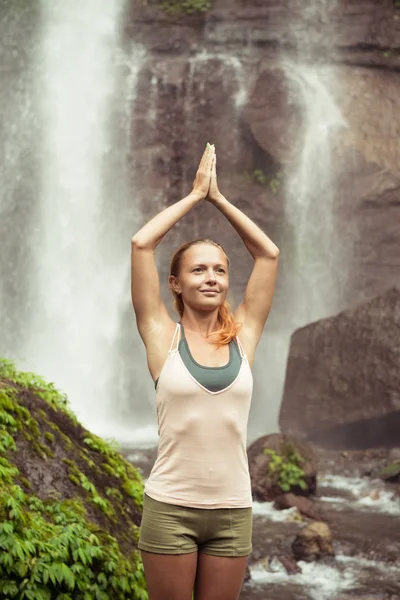 Jeune femme pratiquant le yoga près de la cascade — Photo