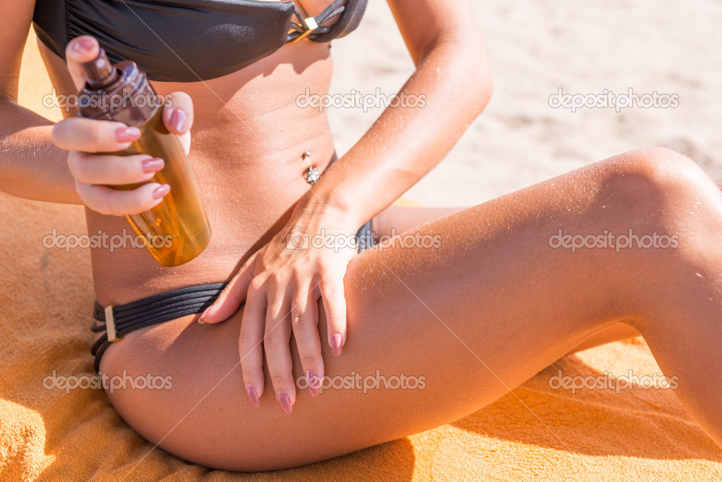 Sensuous slim woman applying suntan oil