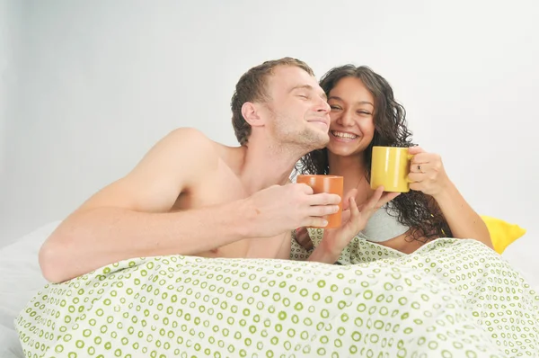 Νεαρό ζευγάρι στο κρεβάτι με καφέ — Φωτογραφία Αρχείου
