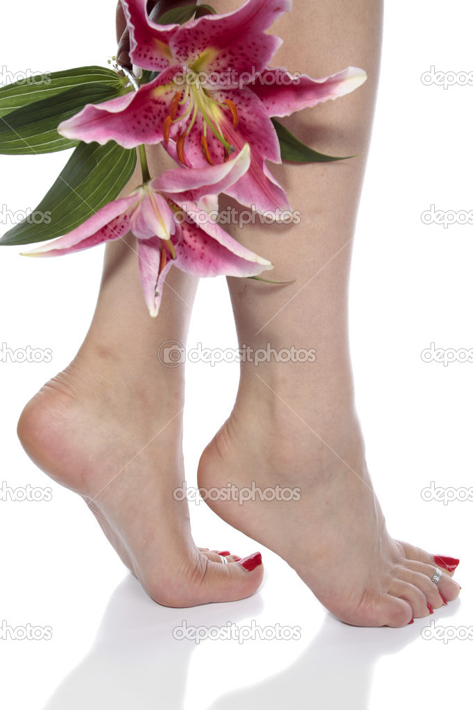 Female feet with lily flowes over white background