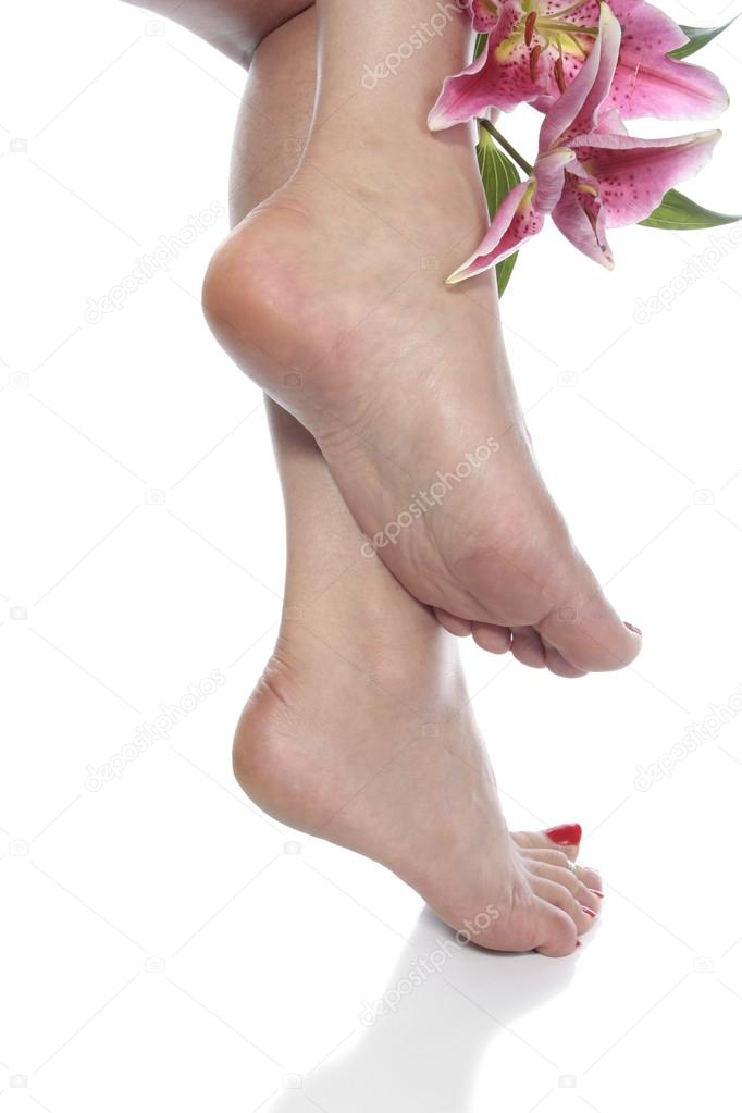 Female feet and flowers over white background