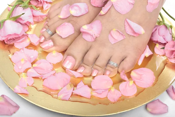 Vacker kvinna fötter med blommor och rosenblad — Stockfoto
