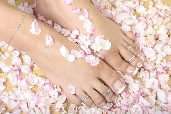 Pieds de femme et pétales de rose — Photo