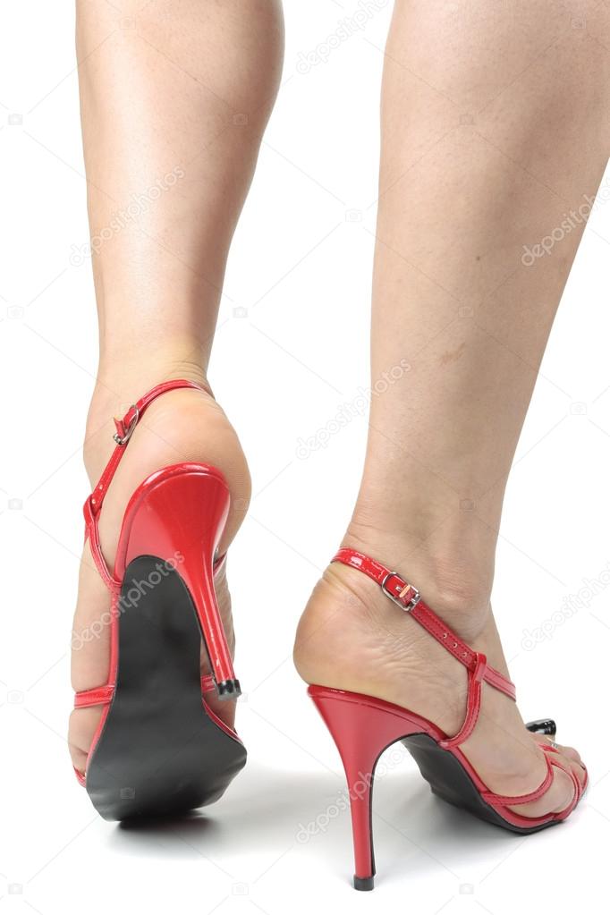 Woman putting on high heel shoes over grey background