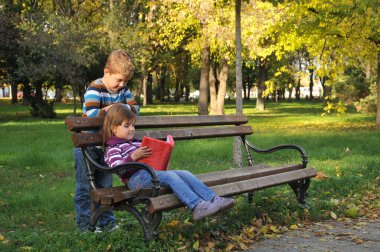 sevimli küçük kız ve erkek sonbahar Park yaprakları ile oynuyor