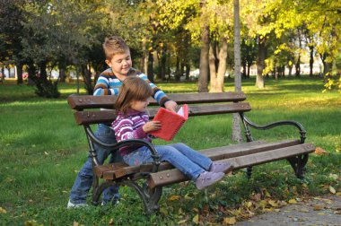 sevimli küçük kız ve erkek sonbahar Park yaprakları ile oynuyor