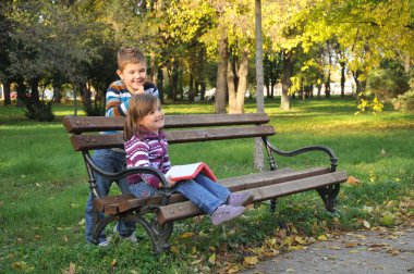 sevimli küçük kız ve erkek sonbahar Park yaprakları ile oynuyor