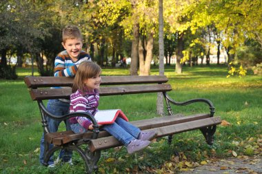 sevimli küçük kız ve erkek sonbahar Park yaprakları ile oynuyor