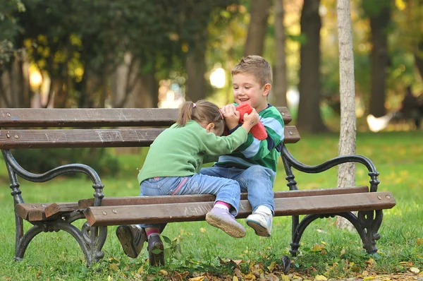 Мальчик и девочка играют в парке купаясь в осенних красках — стоковое фото