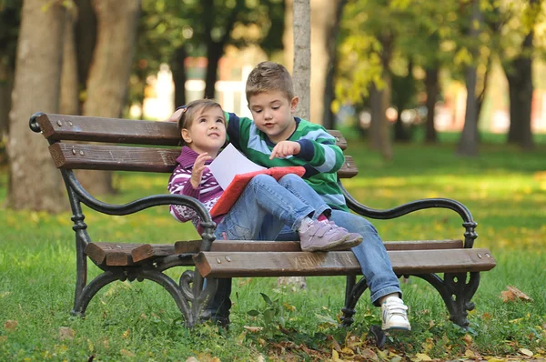 Jongen en meisje in het park spelen badend in de herfst kleuren — Stockfoto