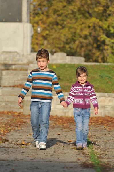Menino e menina brincando no parque banhado em cores de outono — Fotografia de Stock