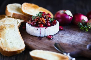 Kızılcık, bal, balzamik sirke, fındık aromalı ve kekikli peynirli fırında peynir. Kızarmış ekmek dilimleri ve taze elmalarla servis edilir. Tatil için geleneksel Fransız peyniri aperatifi. Son derece bulanık seçici odak