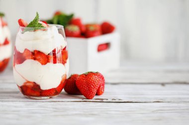 Taze meyveden yapılmış çilekli parfe ve yoğurttan oluşan sağlıklı bir kahvaltı. Öndeki cama odaklan. Bulanık arkaplan ve arkaplan.