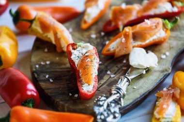 Keto suşisinin üstünde, füme somon ve krem peynirle doldurulmuş mini tatlı biber ve kurutulmuş dereotu. Önplanı ve arkaplanı bulanık seçili odak. 