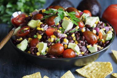 Ev yapımı Meksika fasulyesi ve mısır salatası ya da Teksas havyarı soslu limon sosu, yanında tortilla cipsi ve taze malzemeyle servis edilir..