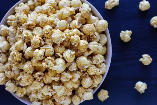 Overhead of close up shot of caramel popcorn in a popcorn bucket. Popular food for movie or cinema snacks. Flat lay. Selective focus with blurred background