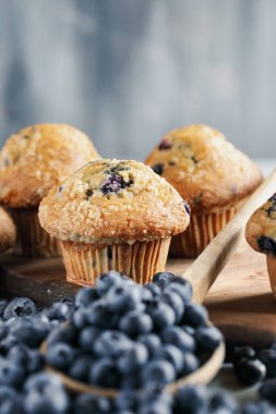 Çiğ yaban mersinli taze yaban mersinli çörekler ahşap kaşıktan dökülüyor. Önplanı ve arkaplanı bulanık olan merkeze seçici odak.
