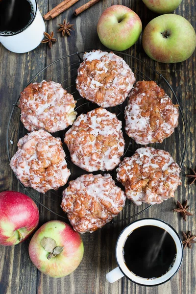 Flatlay of glazed apple fritters and fresh black coffee with fresh apples, cinnamon bark and anise. Top view.