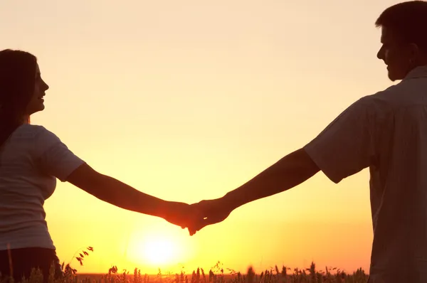 Jeune couple se tenant la main et se regardant l'un l'autre le jour ensoleillé d'été — Photo