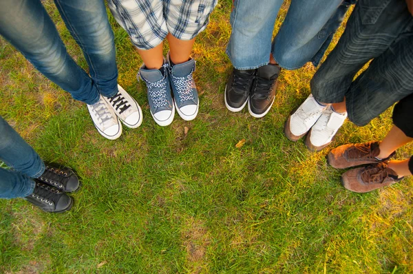 Beine und Turnschuhe von Jungen und Mädchen im Teenageralter, die im Halbkreis auf dem Rasen stehen — Stockfoto