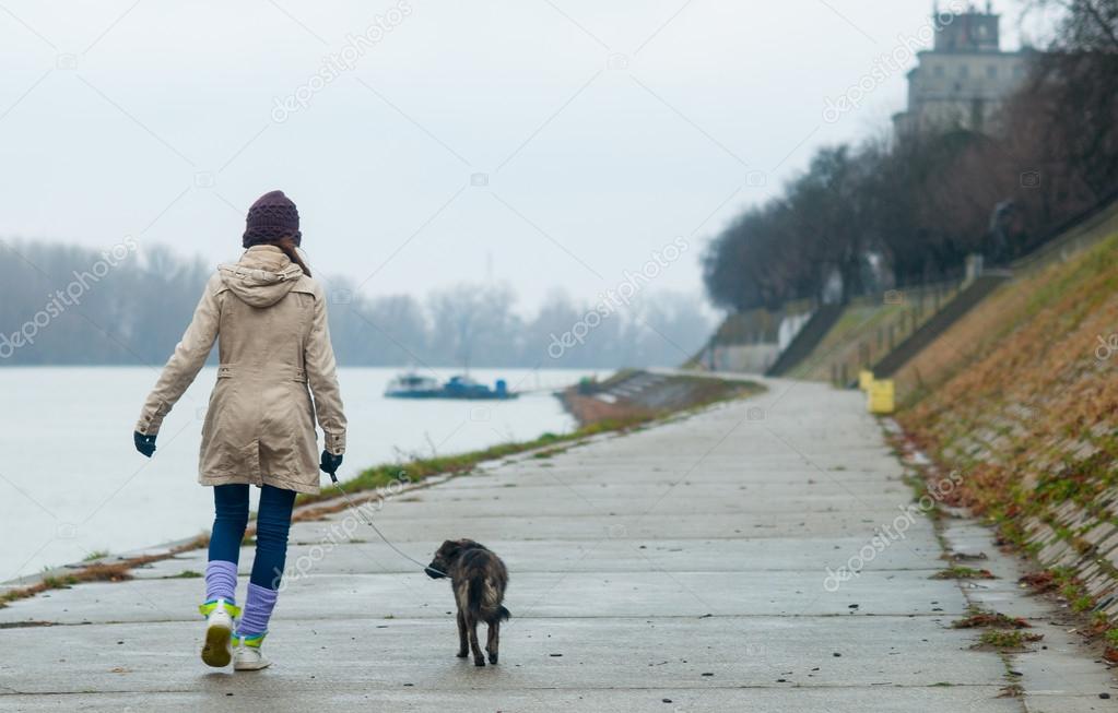 Teenage girl walking the dog on cloudy autumn day
