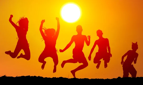 Silhouettes of happy teenagers jumping high in the air on sunny summer day. — Stock Photo, Image